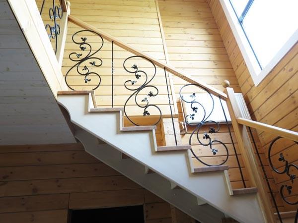 Деревянная лестница с кованными балясинами в интерьере выглядит очень эффектно