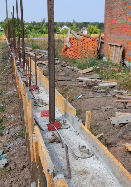 Строительство бетонный фундамент для новых забор с металлическими поддерживает. Строительной площадке во время заливки работает с опалубки бетона — стоковое фото